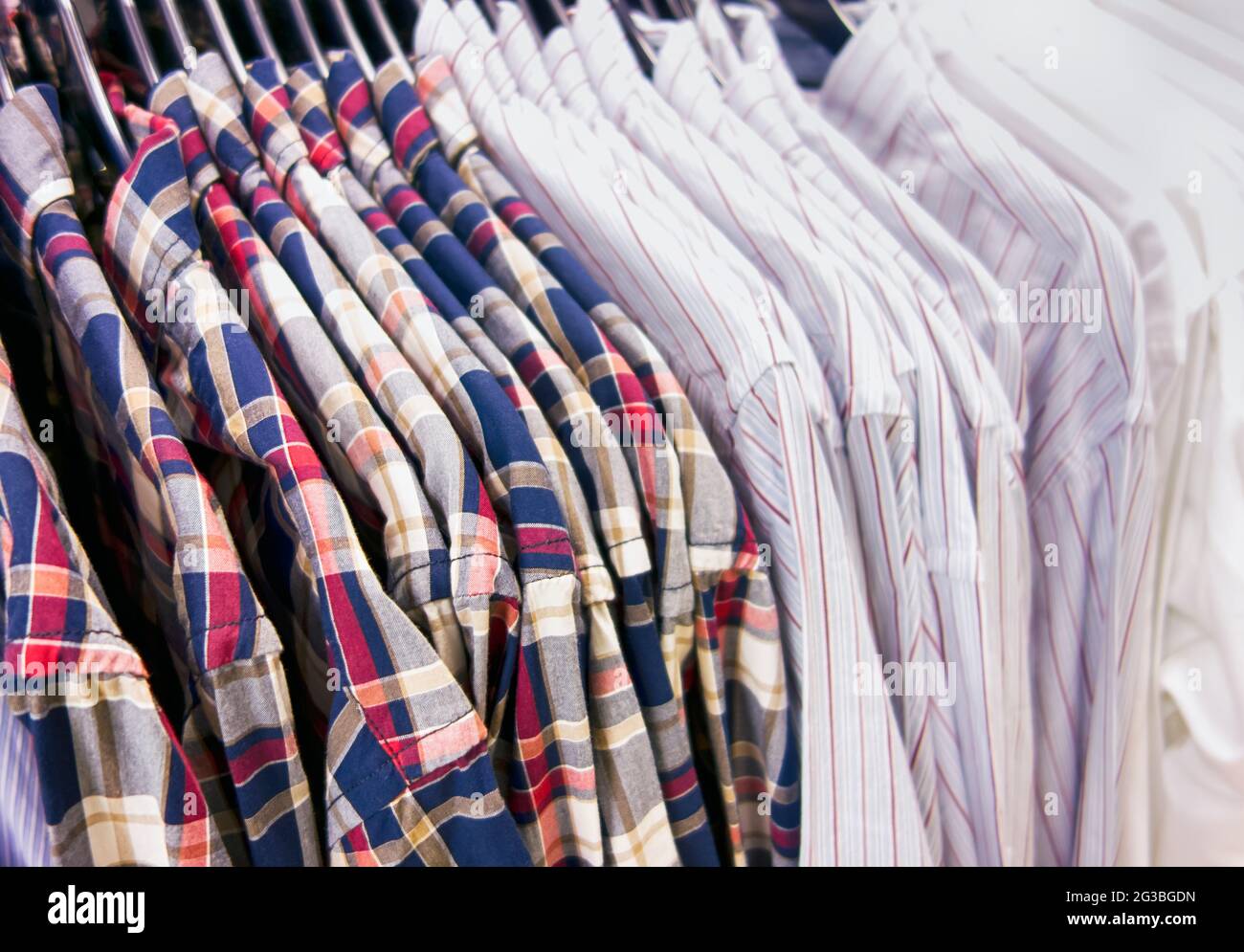 Camicie a manica lunga appese su appendiabiti in un negozio di abbigliamento. Primo piano Foto Stock