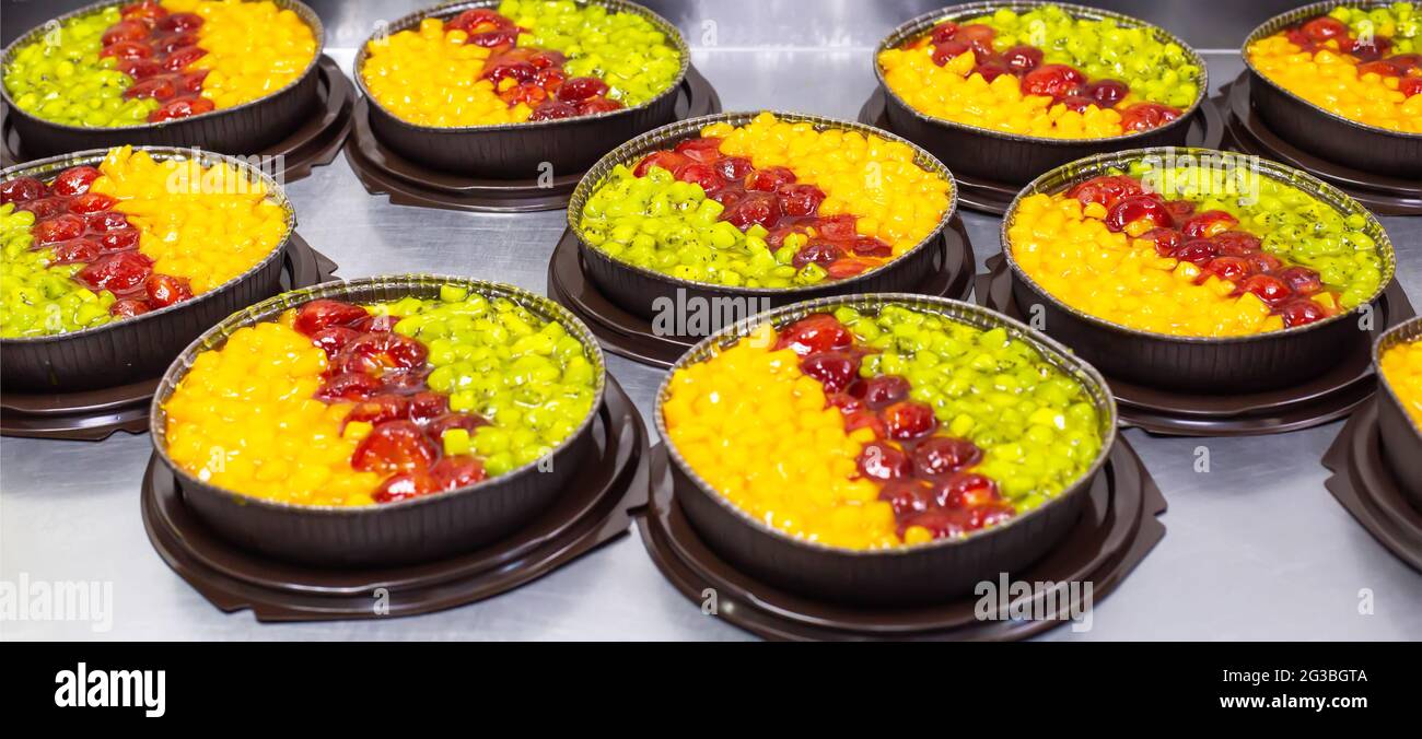 Torte fresche e succose con ananas e kiwi con fragole sciroppate. Dessert estivi freschi, sfondo Foto Stock