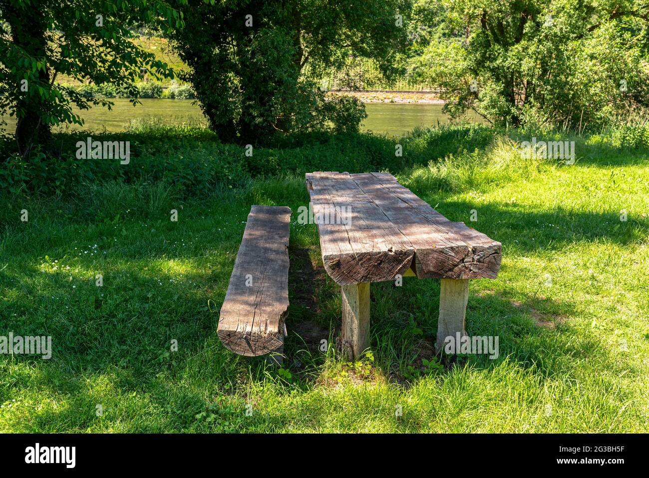 Tavolo lungo con panchine in legno in un prato vicino al fiume. Foto Stock