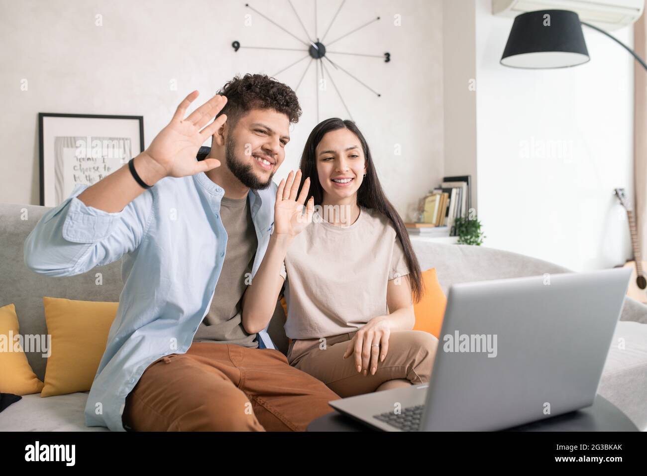 Felice giovane coppia che comunica tramite videochat davanti al laptop Foto Stock