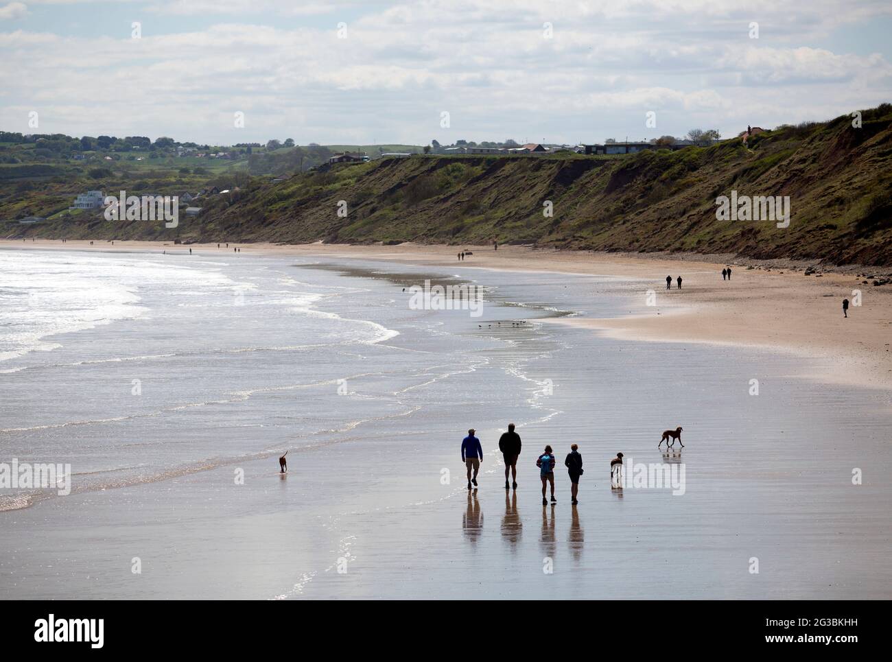 La gente cammina lungo la spiaggia di Filey nel nord dello Yorkshire. Filey è una città costiera sulla costa nord-orientale dello Yorkshire. Un popolare luogo di vacanza per la mattina Foto Stock