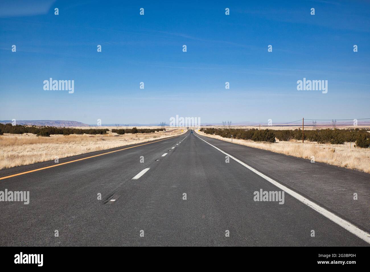 Ammira lungo un lungo tratto di strada attraverso il semi-deserto in Arizona sulla strada per Monument Valley con la strada che converge in lontananza, gli Stati Uniti Foto Stock