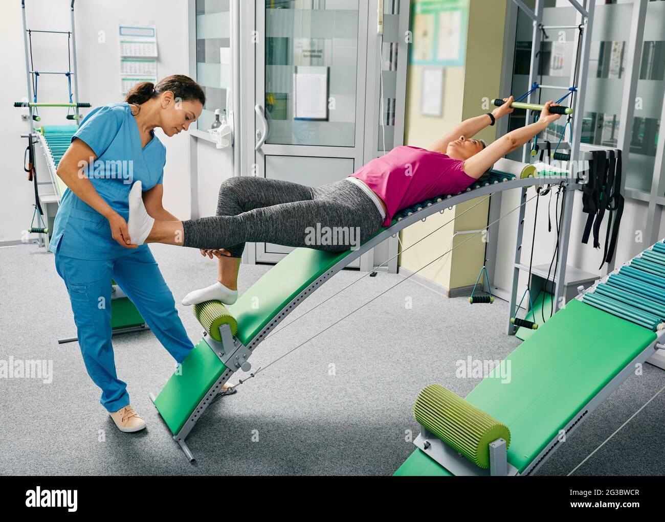 Fisioterapista di razza mista con la sua paziente femminile matura durante la riabilitazione della colonna vertebrale e della schiena Foto Stock