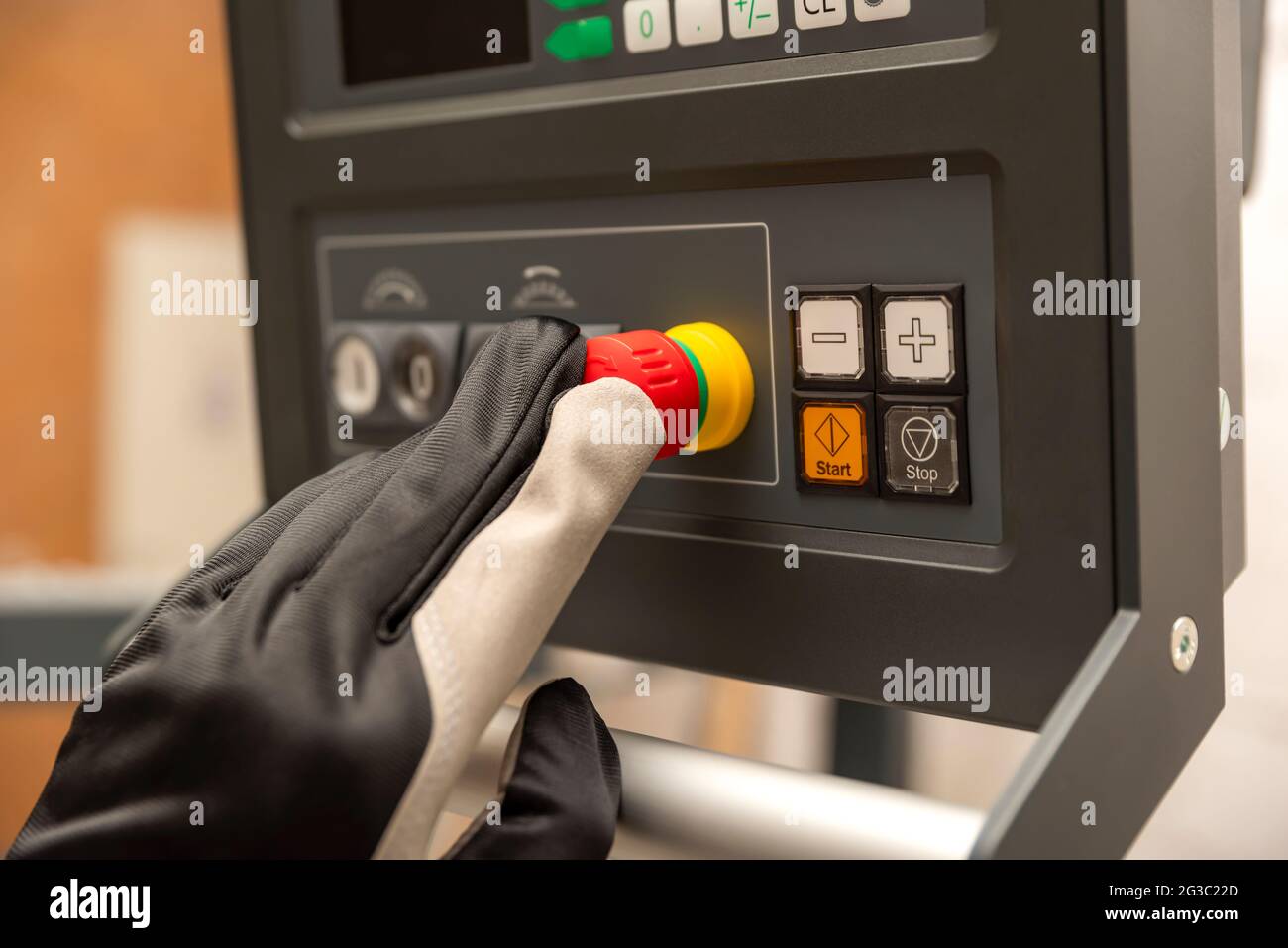 Pulsante di arresto di emergenza in produzione. L'operatore CNC preme il pulsante di emergenza sul pannello di controllo della macchina CNC. Foto Stock