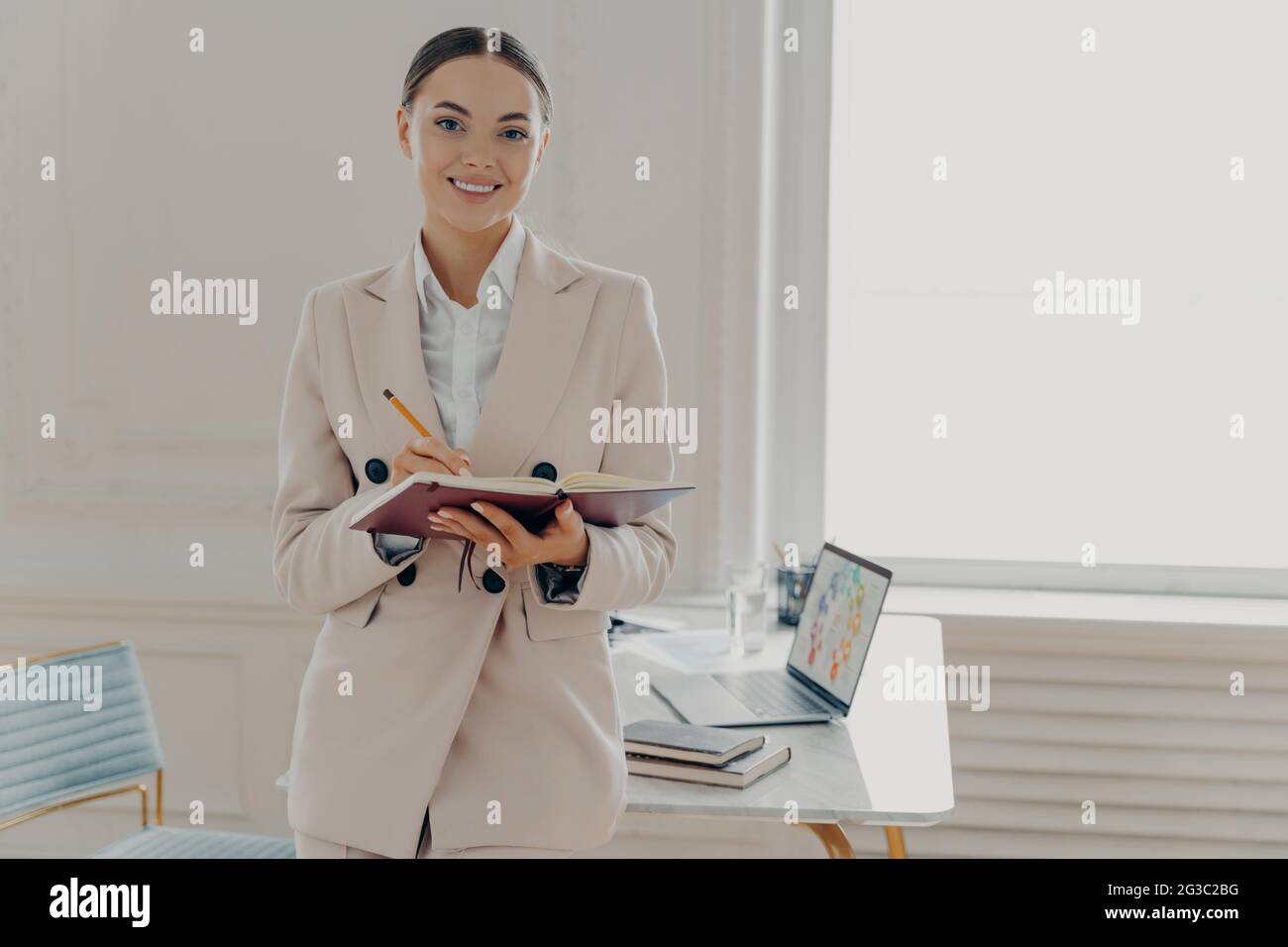 Positiva felice direttrice femminile in un'elegante giornata lavorativa di piallatura dell'usura mentre si trova in ufficio Foto Stock