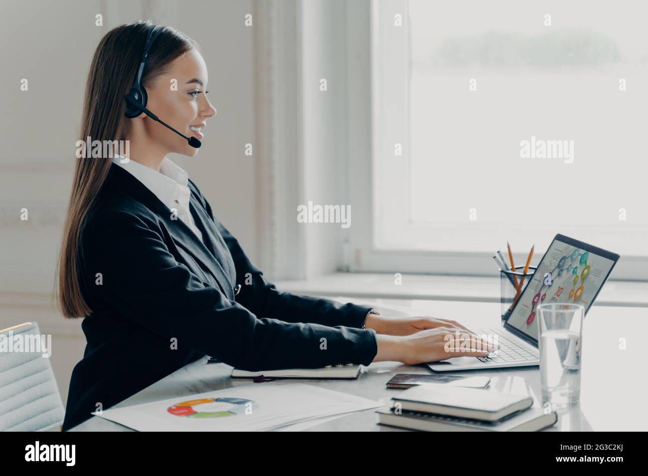 Donna professionale che indossa una cuffia che lavora con i dati finanziari durante la riunione online Foto Stock