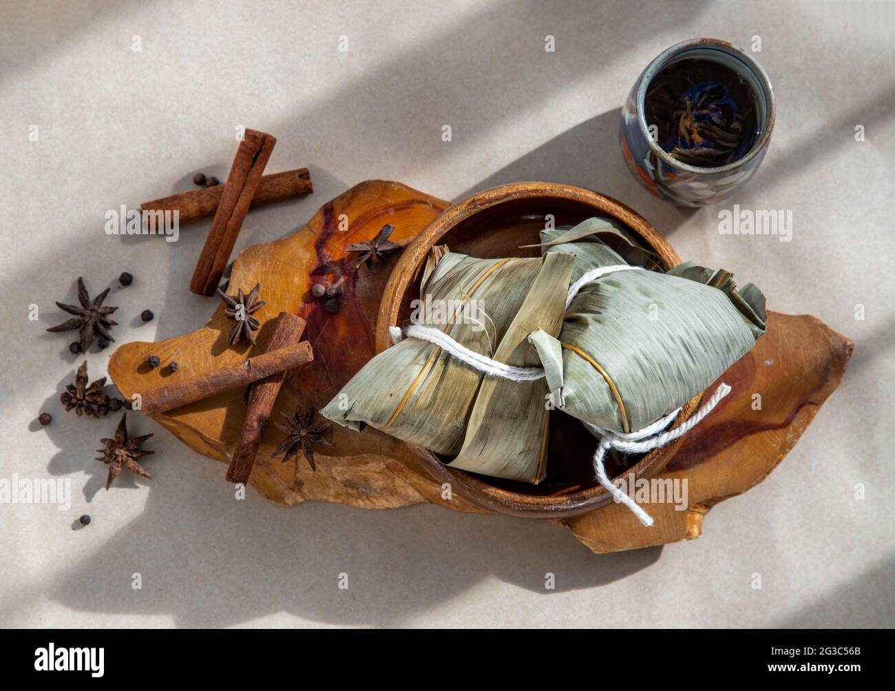 Gnocchi di riso cinese (Zongzi) a forma di piramide avvolto da foglie ingredienti su piastra di legno. Famoso cibo asiatico gustoso fatto a mano in barca drago (duan Foto Stock