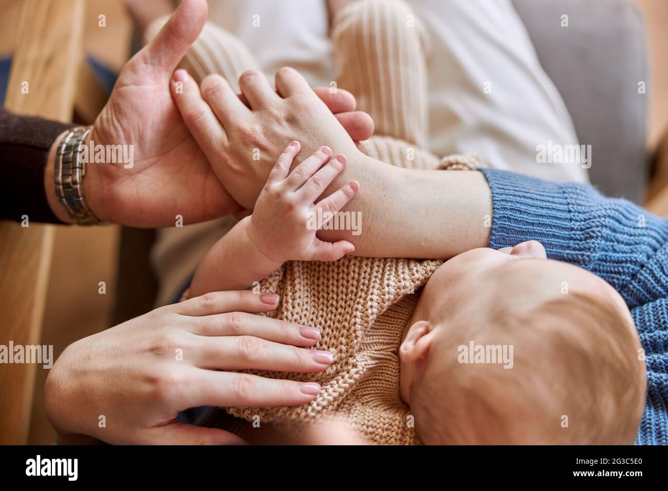 Madre e padre toccano le mani del neonato Foto Stock