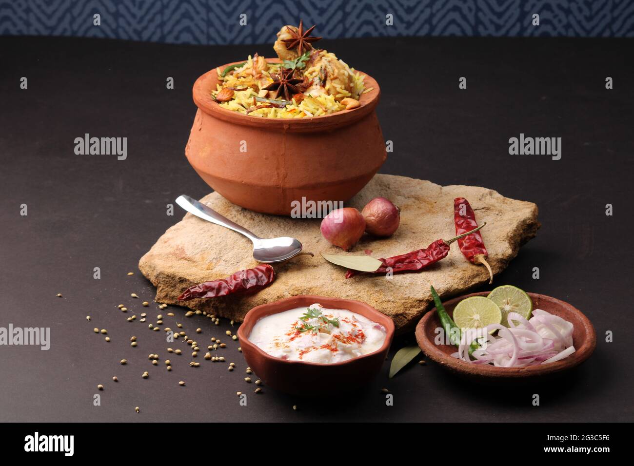 Pollo piccante dum biryani in tradizionale handi o creta pentola. Servito con raita di cipolla Foto Stock