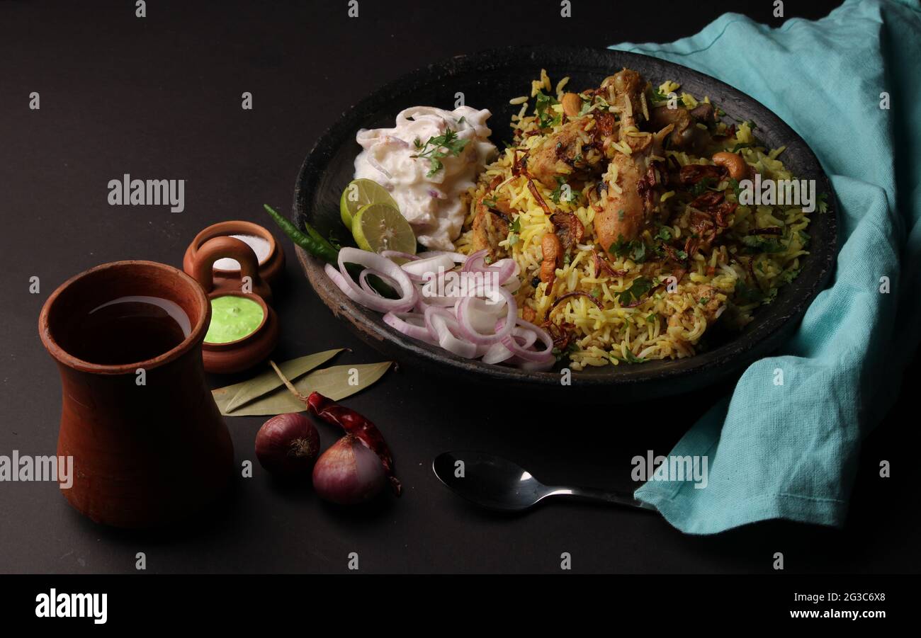 Pollo piccante dum biryani in tradizionale handi o creta pentola. Servito con raita di cipolla Foto Stock