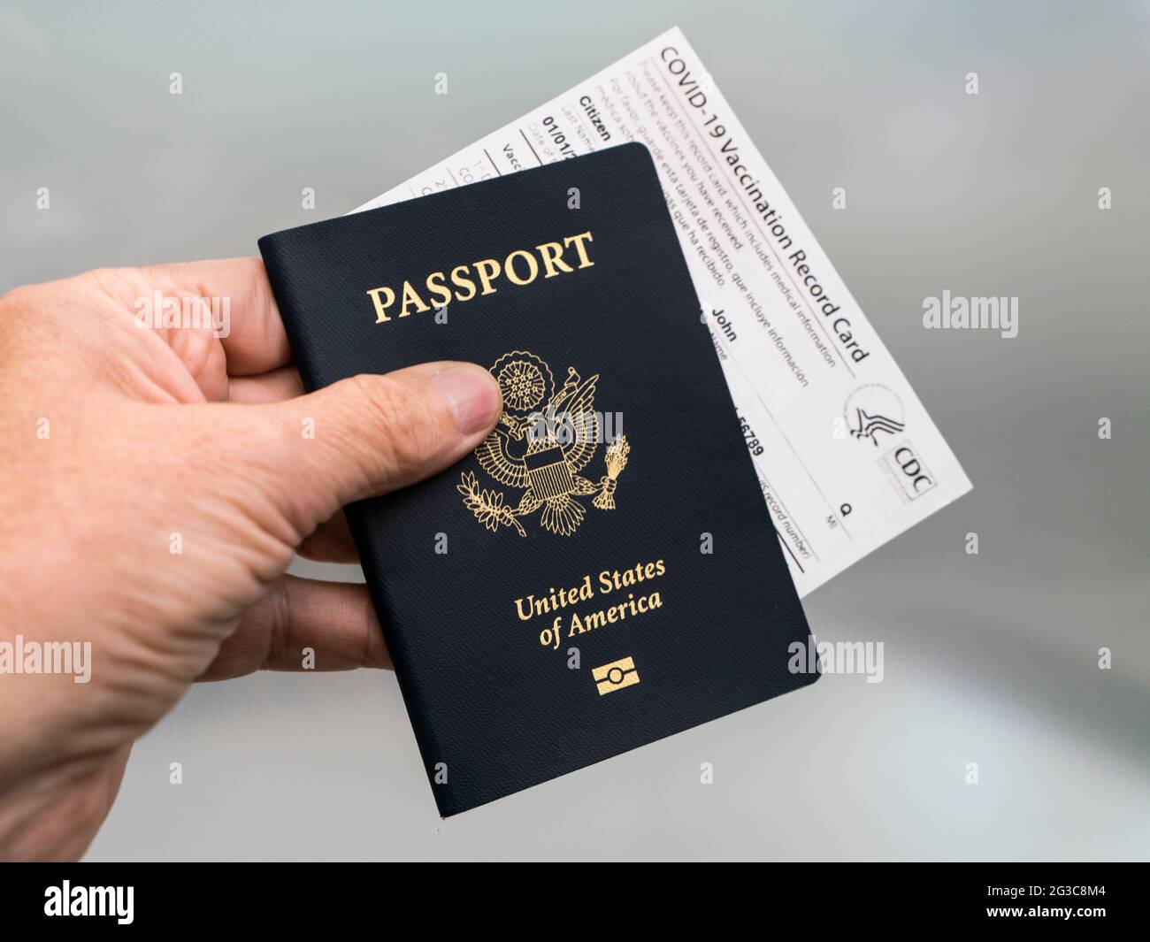 Costa Mesa, CA - 16 marzo 2021: Passaporto per mano dell'uomo e scheda ufficiale di vaccinazione Covid-19 Foto Stock