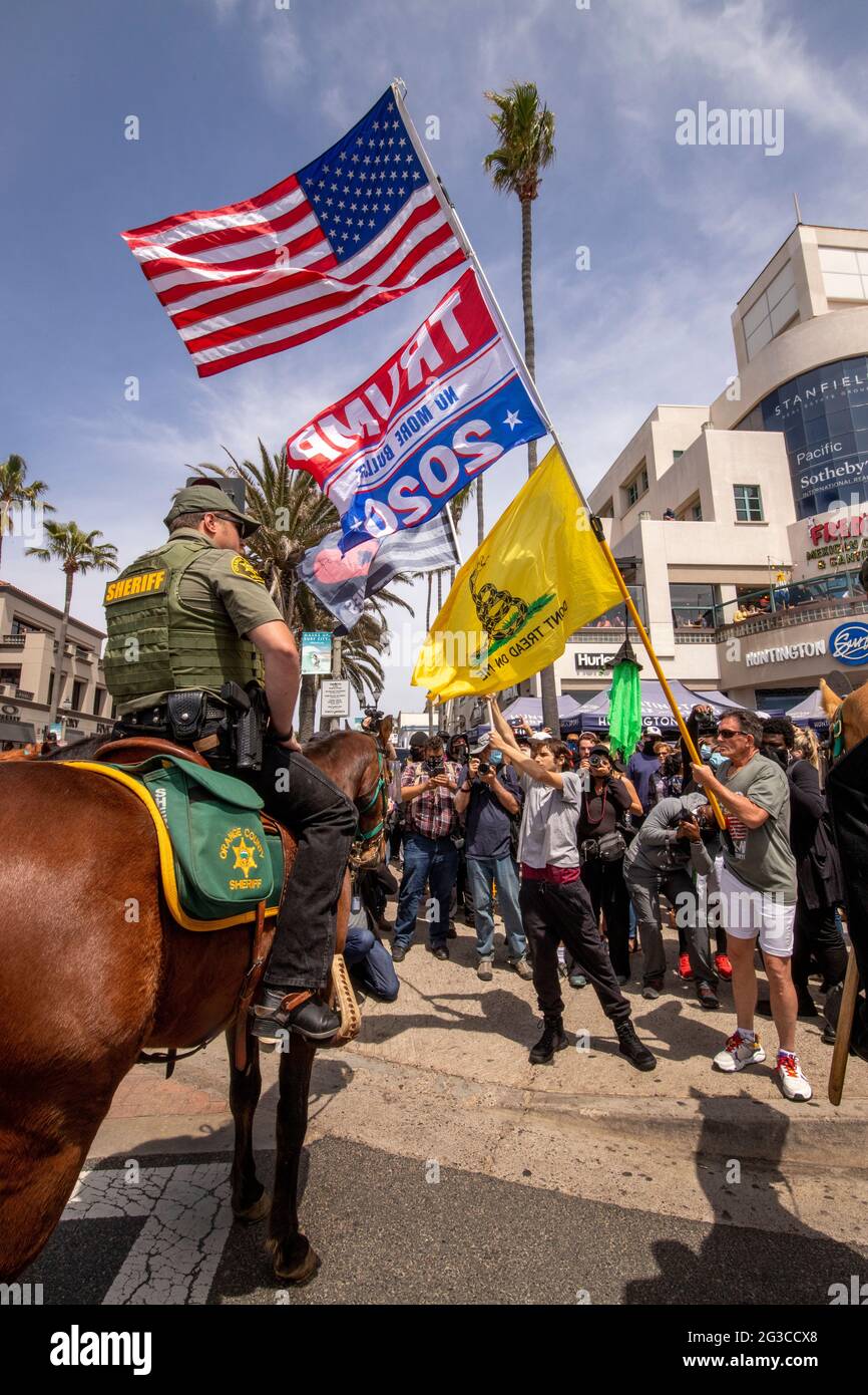 I sostenitori caucasici di Donald Trump marciano per protestare contro la sconfitta elettorale del 2020 a Huntington Beach, California, sotto l'occhio vigile di uno sceriffo montato Foto Stock