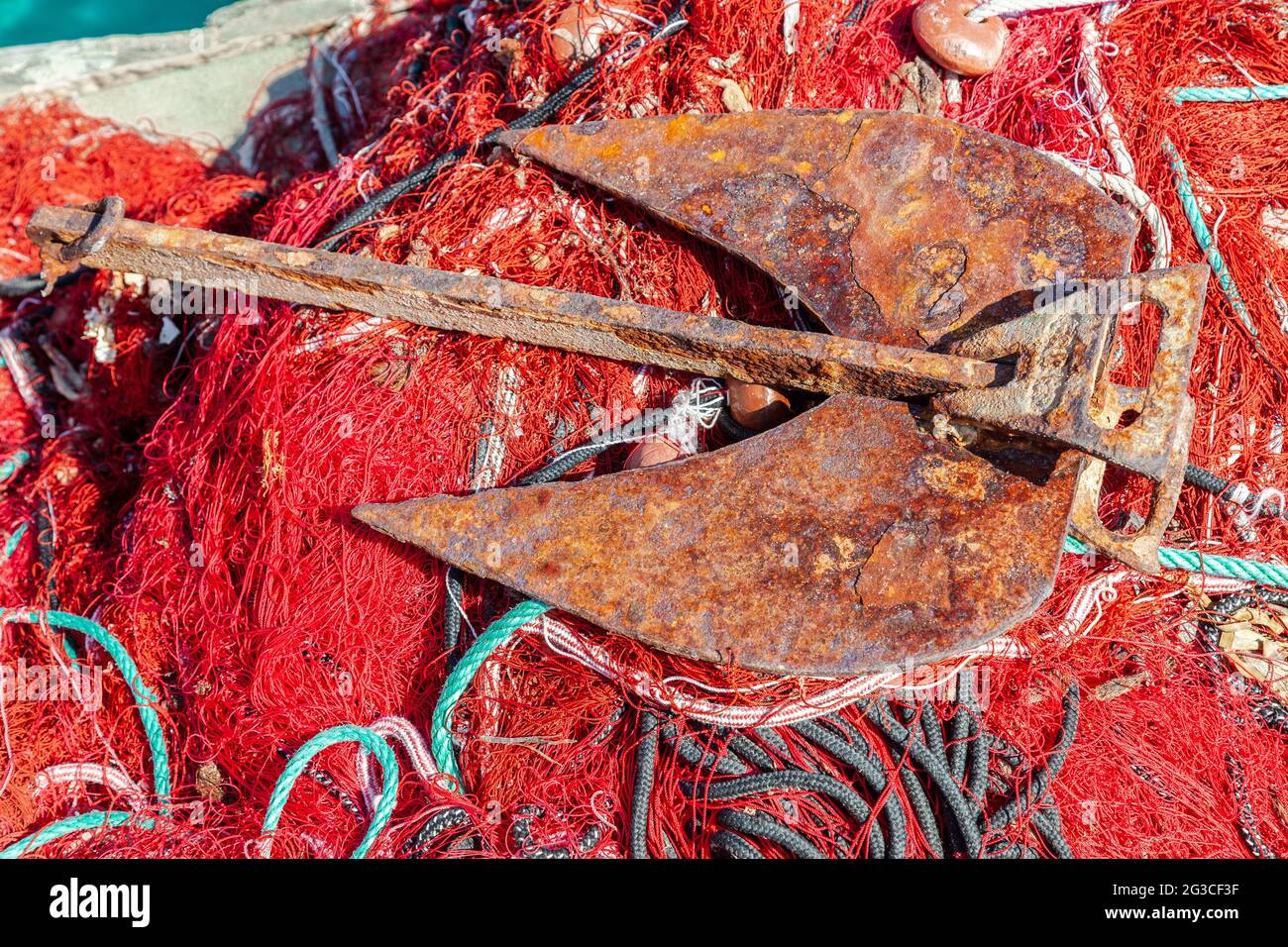 Ancora arrugginita posta su una rete da pesca rossa. Campomoro. Corsica, Francia Foto Stock
