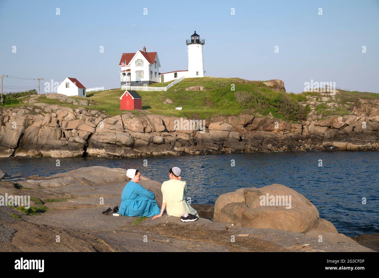 Due ragazze Amish che si divertono una serata al Nubble Light a Cape Neddick (York), Maine, USA Foto Stock