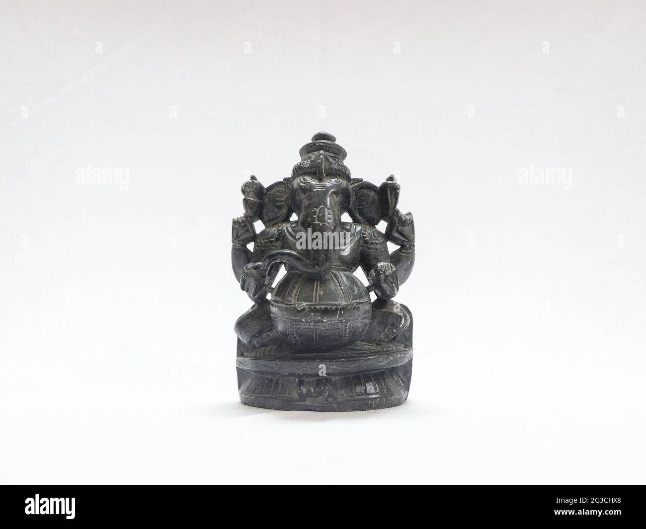 Primo piano di una piccola scultura rupestre di Ganesha isolata su sfondo bianco Foto Stock