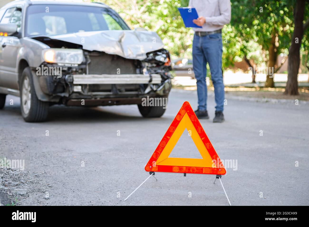 L'agente di assicurazione uomo descrive l'evento assicurato con l'automobile distrutta dopo l'incidente dell'automobile. Assicurazione auto su strada. Uomo con tablet che prende le letture dopo l'incidente Foto Stock