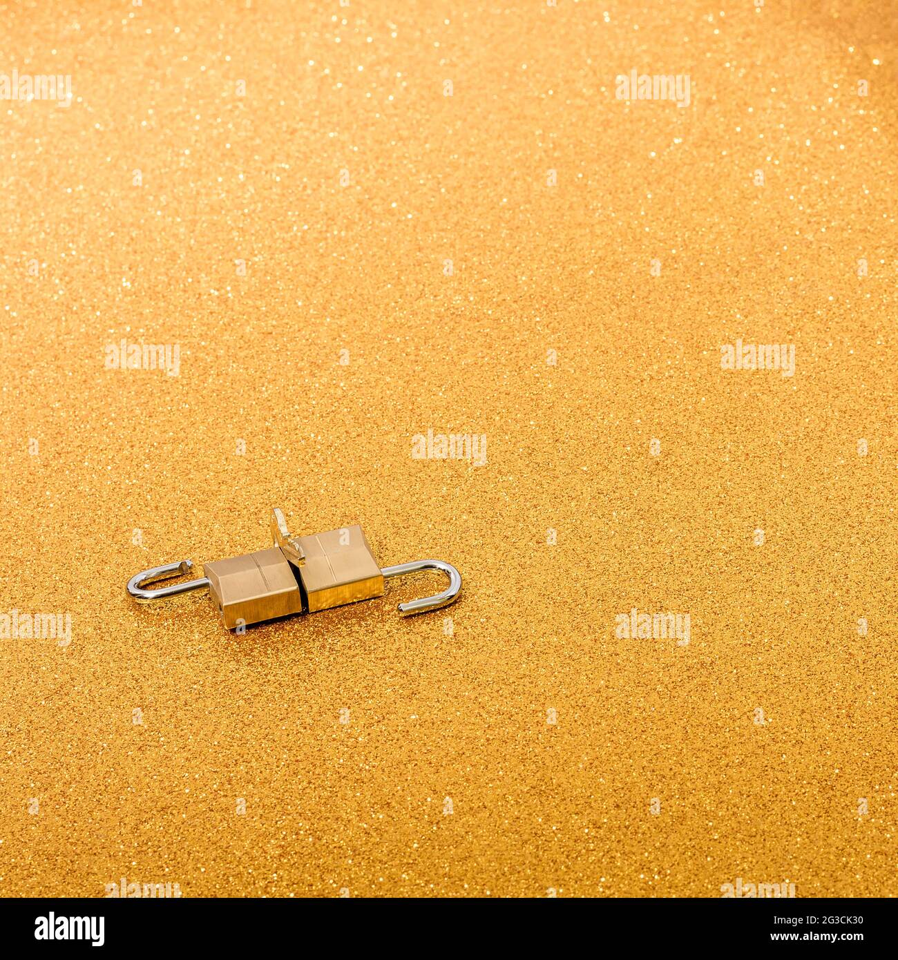 Lucchetti dorati e piccola chiave su uno sfondo color oro.la fotografia ha spazio per mettere il testo che si desidera.la foto ha un formato quadrato. Foto Stock