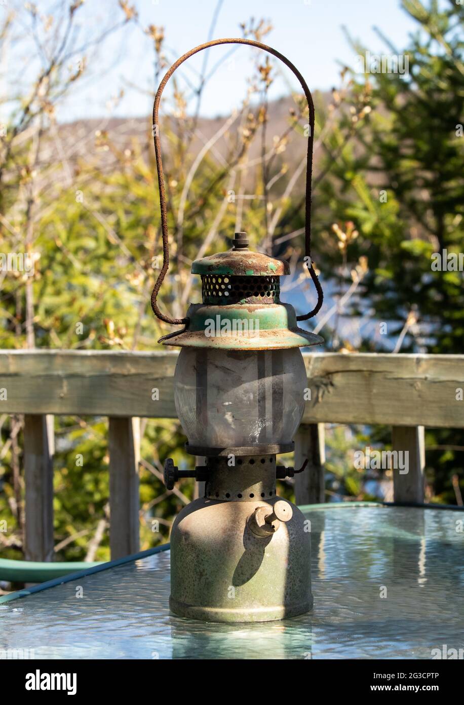 lampada a gas molto vecchia, arrugginita e polverosa, per esterni su un  tavolo di vetro accanto a una recinzione in una giornata di sole Foto stock  - Alamy