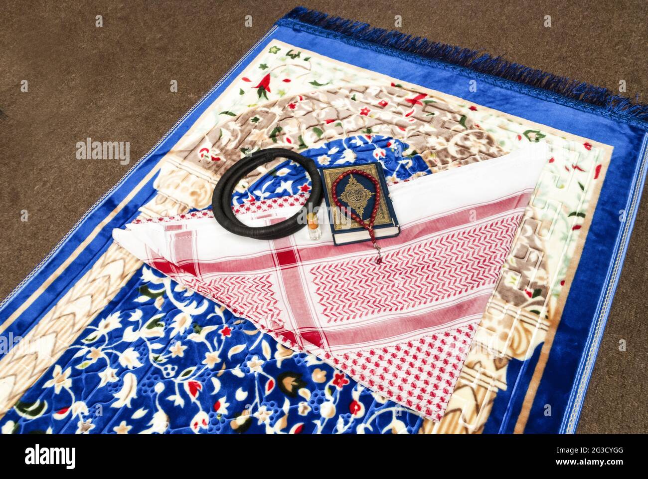 Set di accessori per la preghiera religiosa islamica, bottiglia del profumo di shemagh del rosario Quran AGAL sul tappetino di preghiera, vista dall'alto Foto Stock