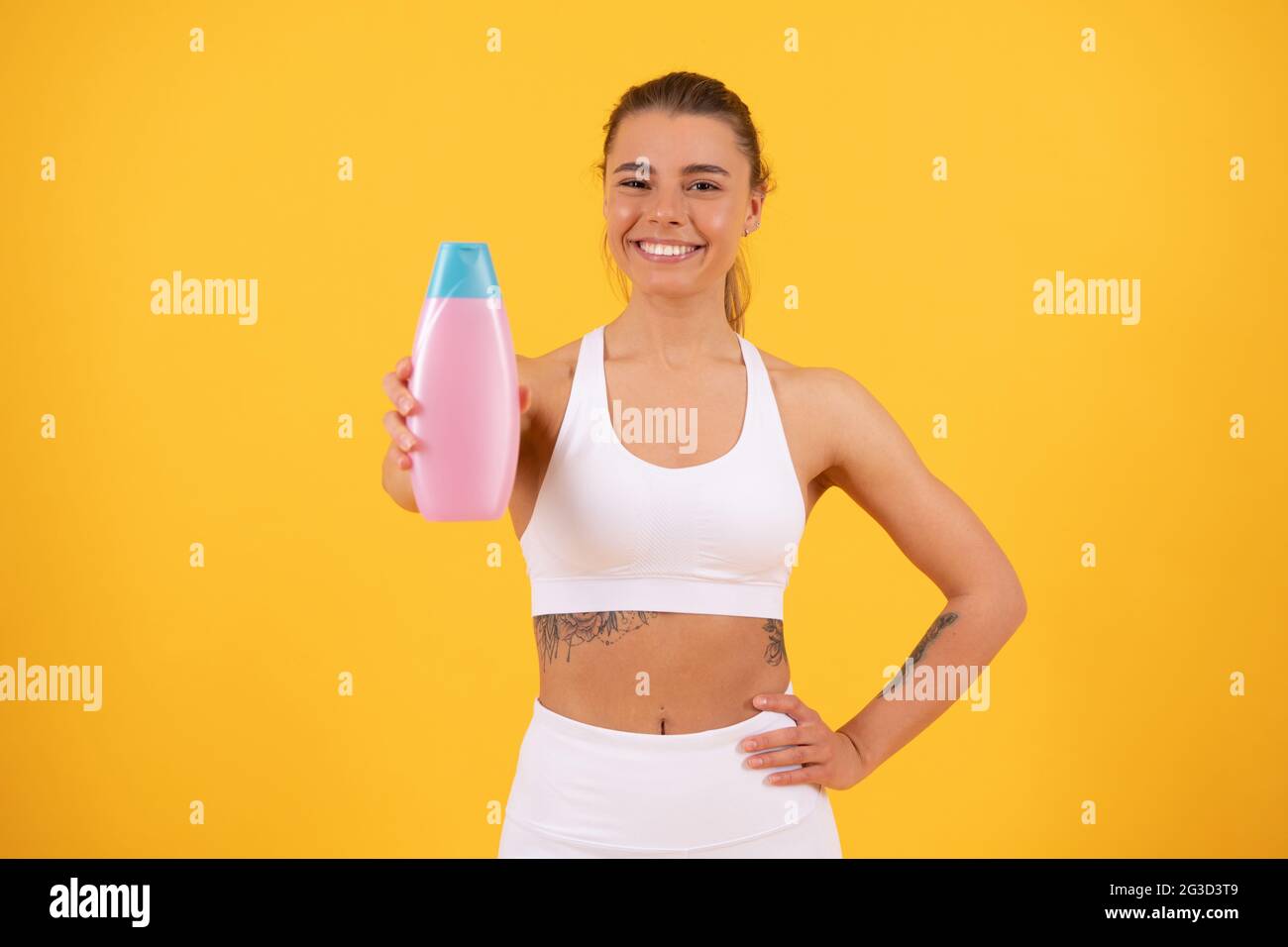 felice ragazza mostrando bottiglia di shampoo balsamo capelli balsamo o lozione corpo, abitudine quotidiana Foto Stock