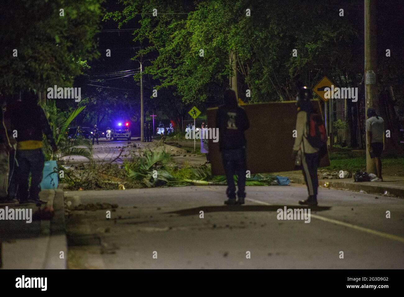 Manifestanti della guardia di prima linea da barattoli a gas lacrimogeni e granate stunt dietro una matress come dimostranti e la polizia in rivolta della Colombia (ESMAD) scontro durante la notte del 14 giugno 2021, a Yumbo - Cali, Valle del Cauca - Colombia come le proteste anti-governative si svelano nella loro settima settimana contro il governo del presidente Ivan Duque, disordini e violenze che avevano causato almeno 70 morti. Foto Stock