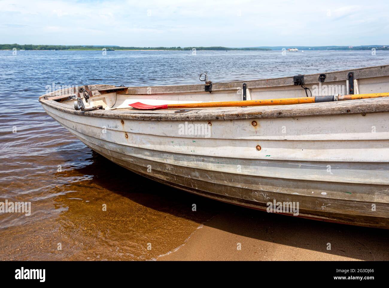 Barca di pesca in legno sulla riva sabbiosa del fiume nel giorno d'estate Foto Stock