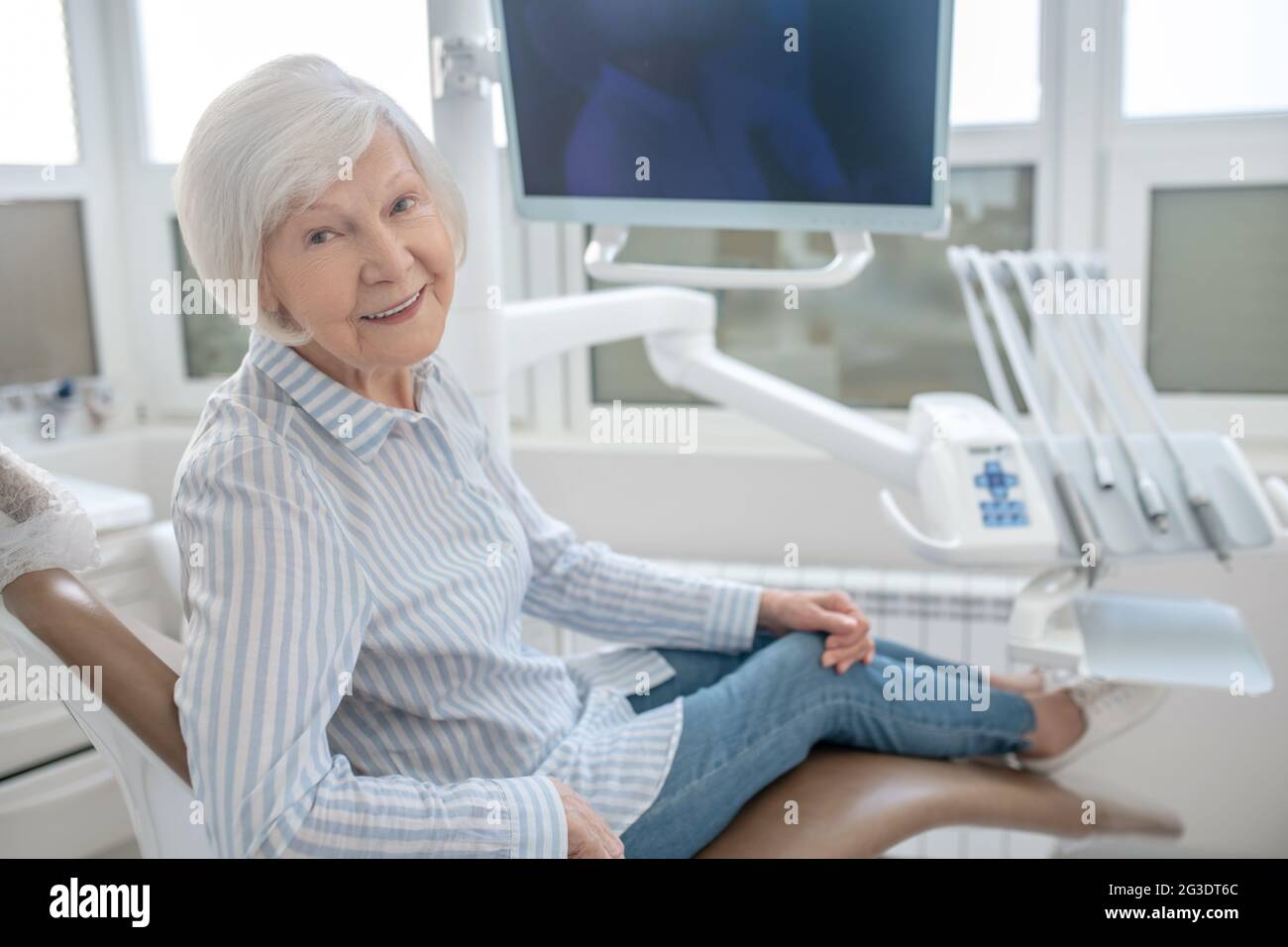 Donna dai capelli grigi seduta presso l'ufficio dei dentisti e in attesa del medico Foto Stock