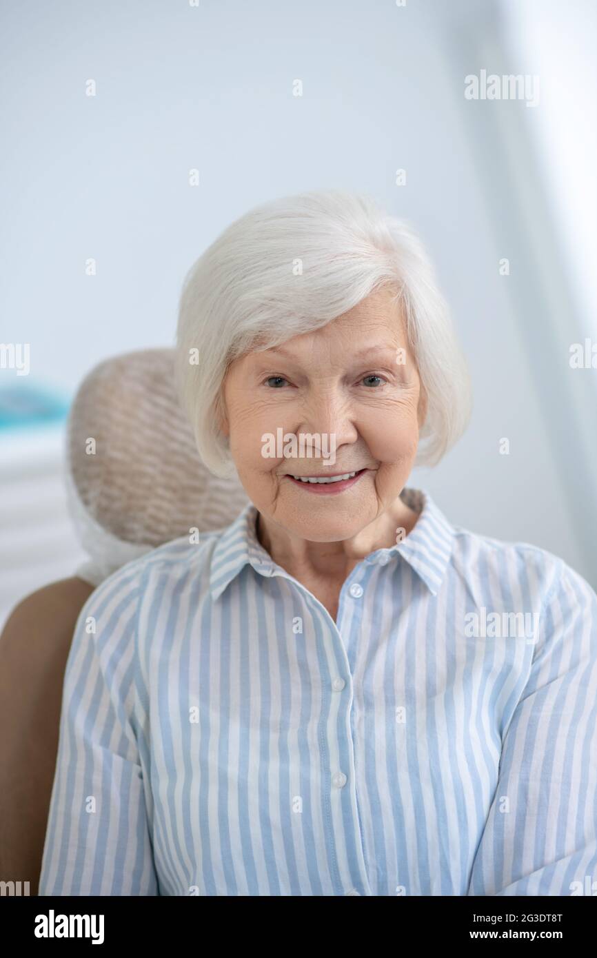 Primo piano di una donna dai capelli grigi che sorride piacevolmente Foto Stock
