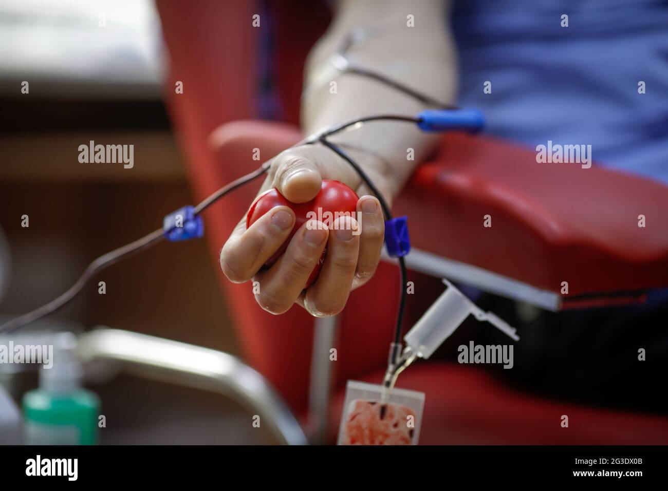 Profondità di campo poco profonda (fuoco selettivo) con la mano di un uomo che dona sangue. Foto Stock