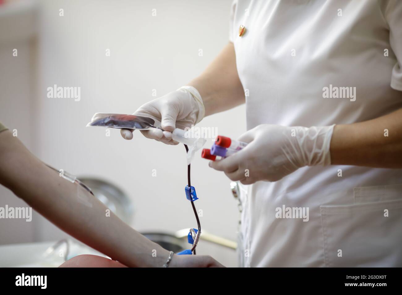 Profondità di campo poco profonda (fuoco selettivo) con le mani di un lavoratore medico che prepara un volontario per la donazione di sangue. Foto Stock