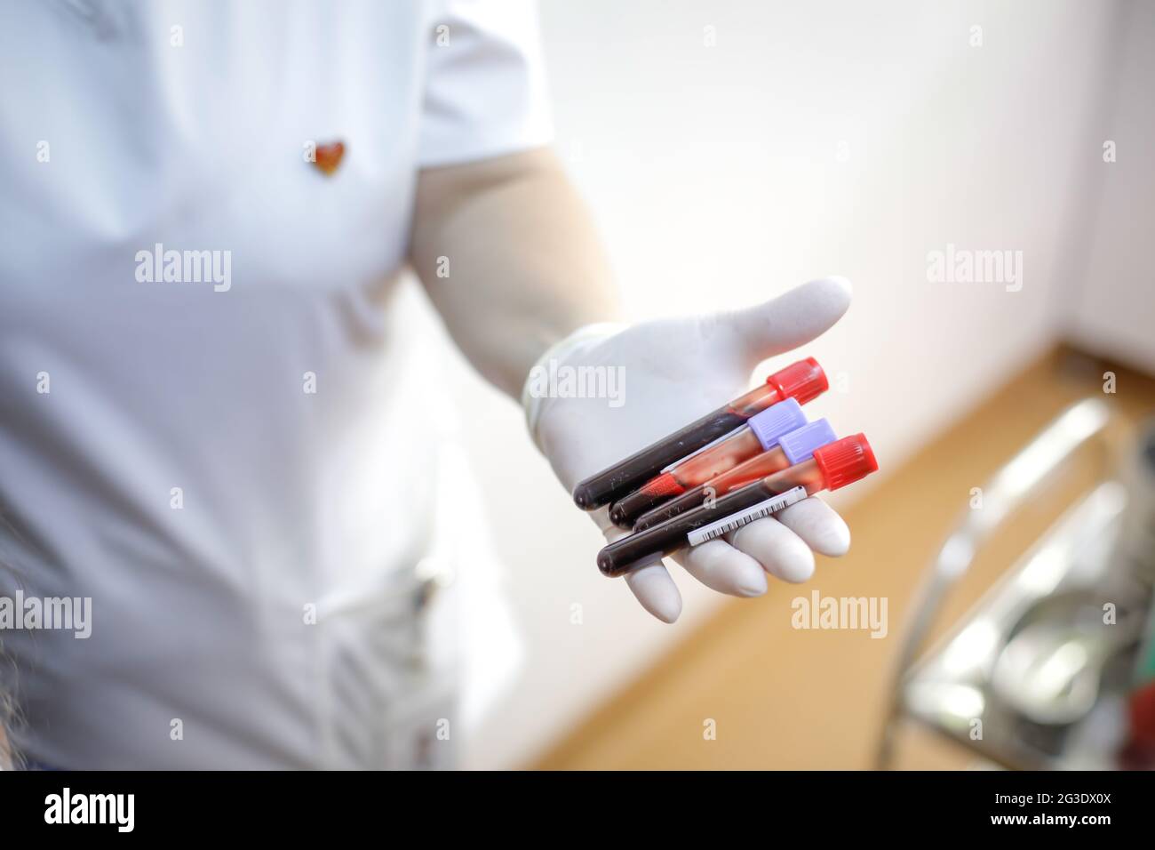 Dettagli della profondità di campo poco profonda (fuoco selettivo) con una operatrice medica femminile che tiene fiale di sangue dopo una donazione di sangue. Foto Stock