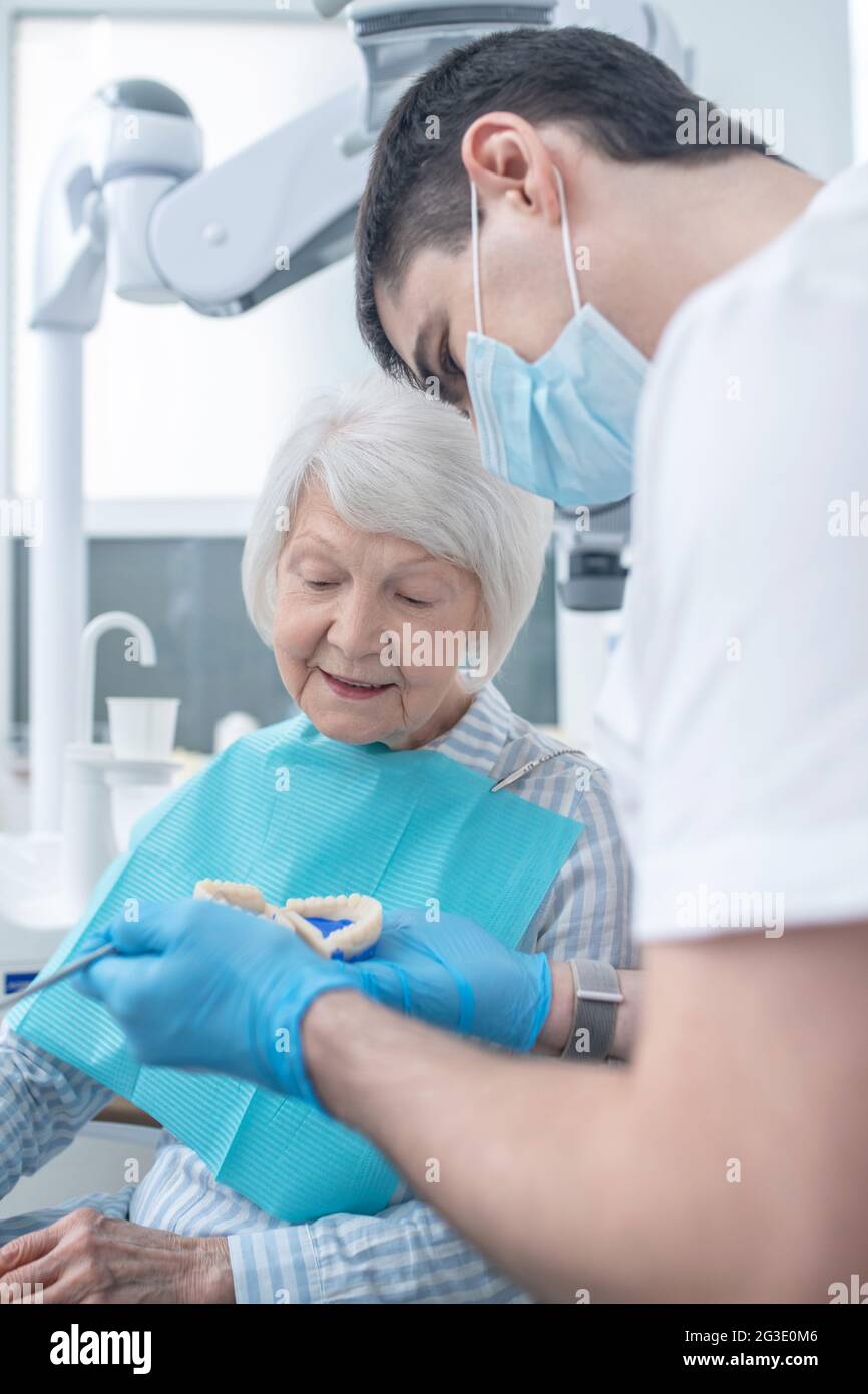 Chirurgo dentale maschile che mostra la dentiera al suo npatient Foto Stock