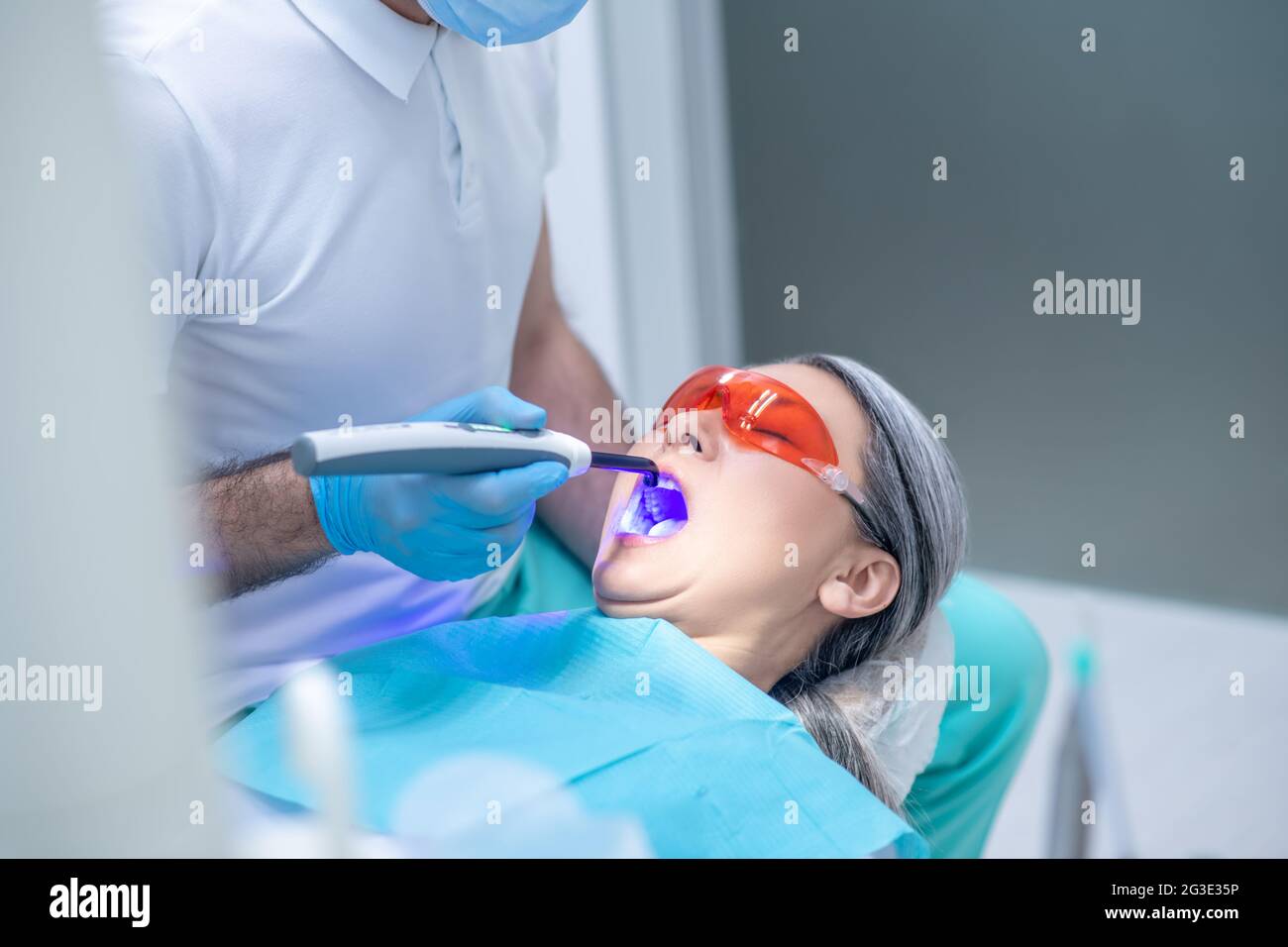 Donna in occhiali protettivi che ha un restauro dentale presso l'ufficio dei dentisti Foto Stock