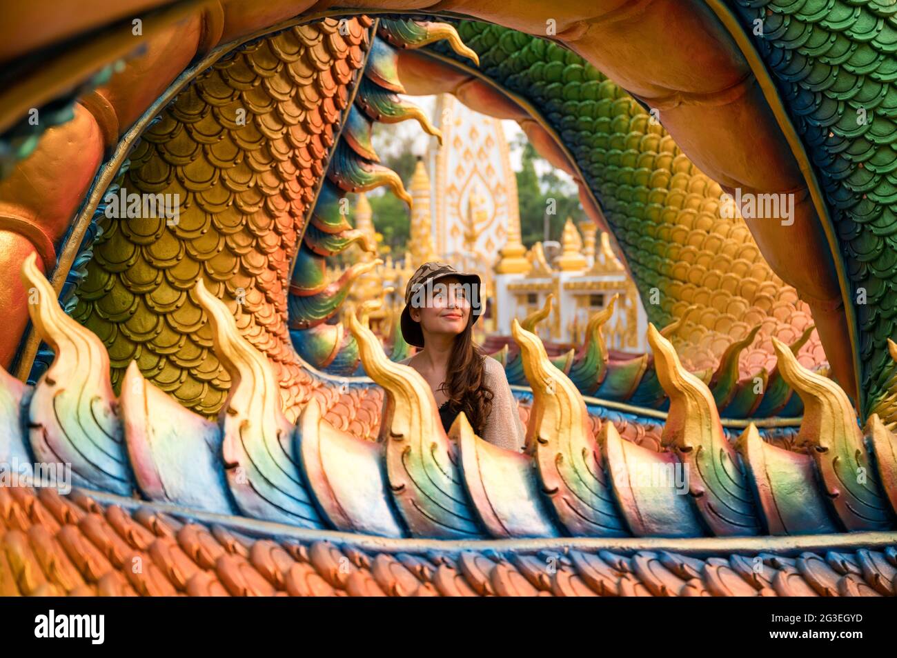 Felice giovane donna asiatica sorridente in colorata statua serpente a Wat Phra che tempio Nong Bua, Ubon Ratchathani Foto Stock