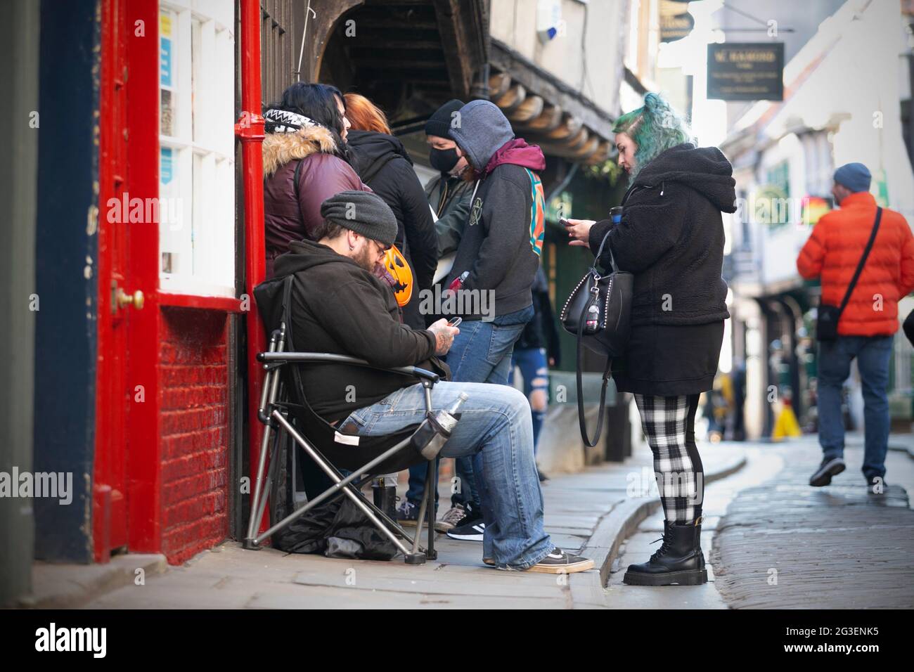 La gente coda in attesa di mattina presto per le porte di riaprire al di fuori del negozio di mercanti fantasma York negli Shambles a York, North Yorkshire come negozi pr Foto Stock