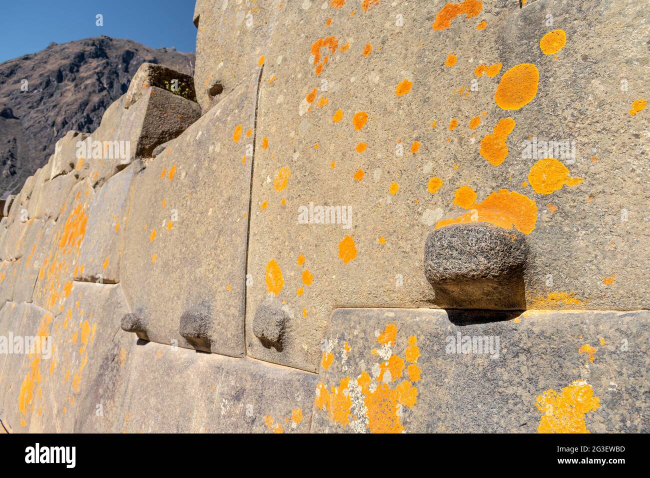 Parete in pietra inca realizzata con pietre perfettamente adattate ricoperte di lichene arancione alle rovine di Ollantaytambo, Perù Foto Stock