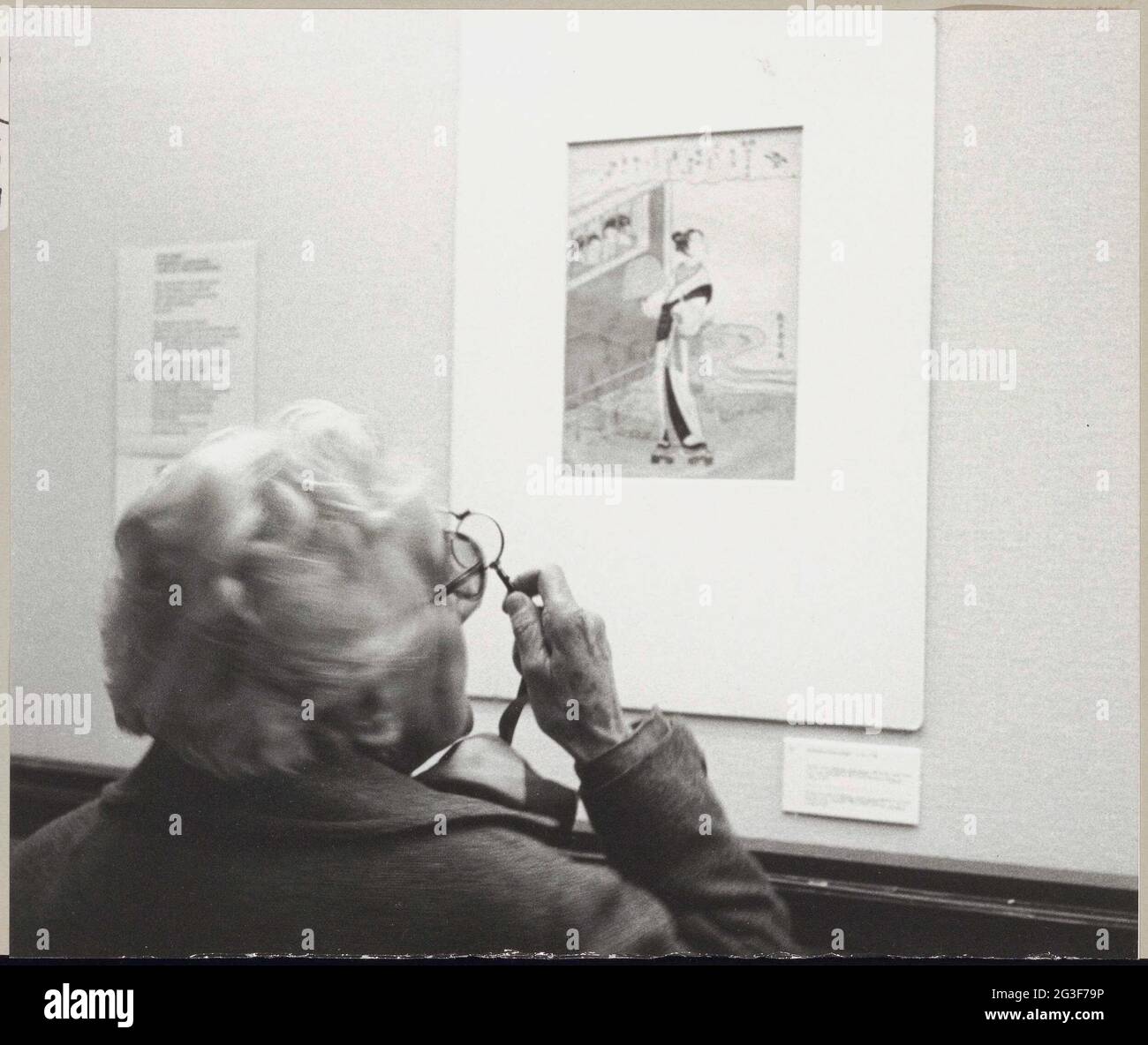 Visitatore con bicchieri e Lornnet a una stampa di osservazione sulla parete; mostra Harunobu. . Foto Stock