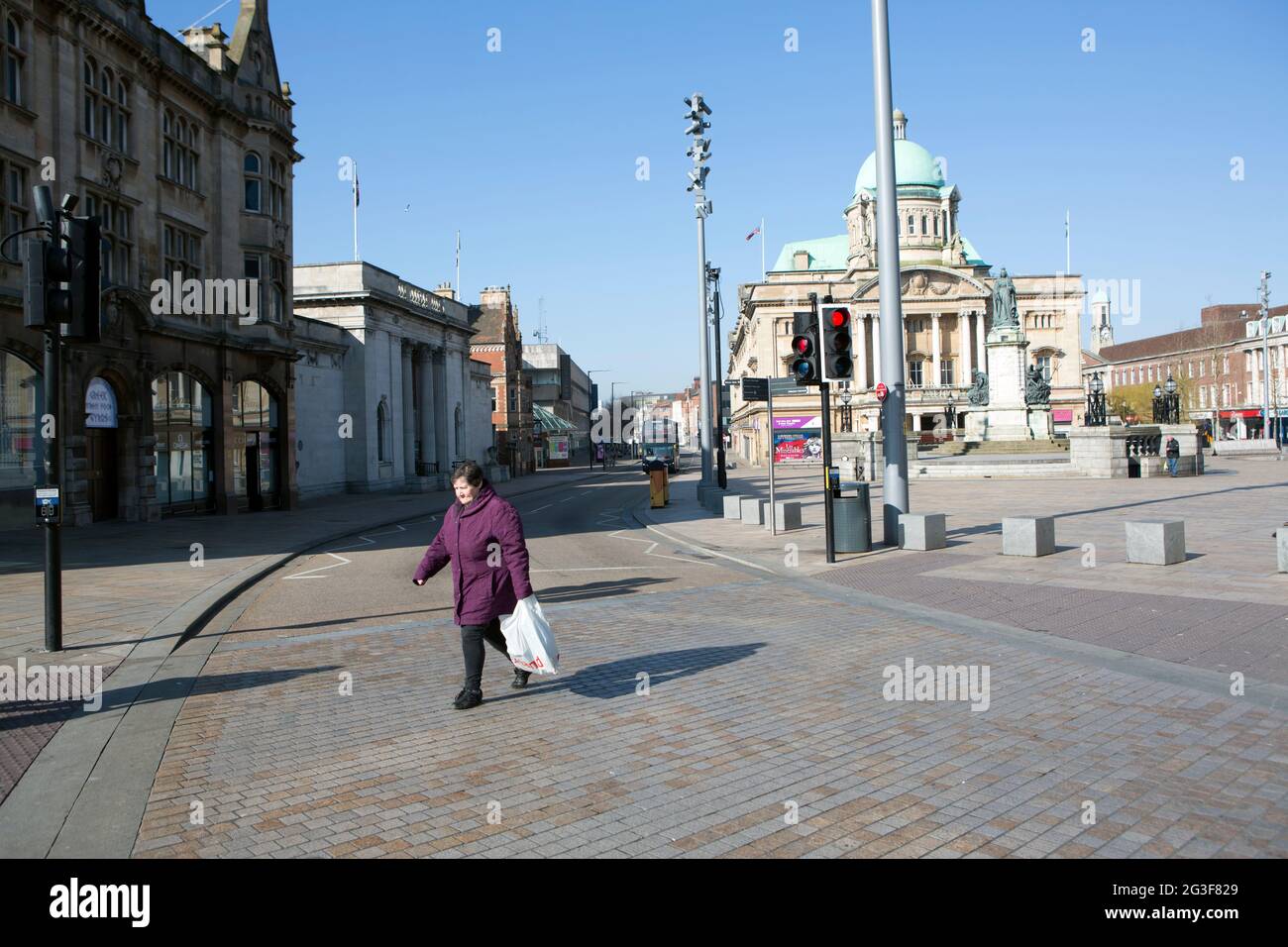 Una signora anziana si infila di fronte alla strada di Hull City Hall sulle strade vuote e deserte del centro di Hull City, mentre l'epidemia di Coronavirus si è protratta Foto Stock