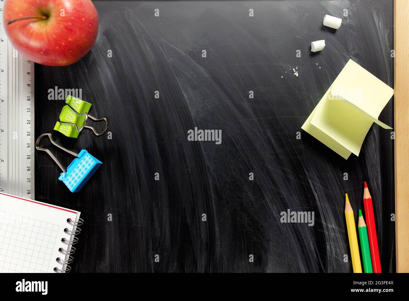 Posa piatta con piccolo sfondo nero della scuola con accessori scolastici Foto Stock