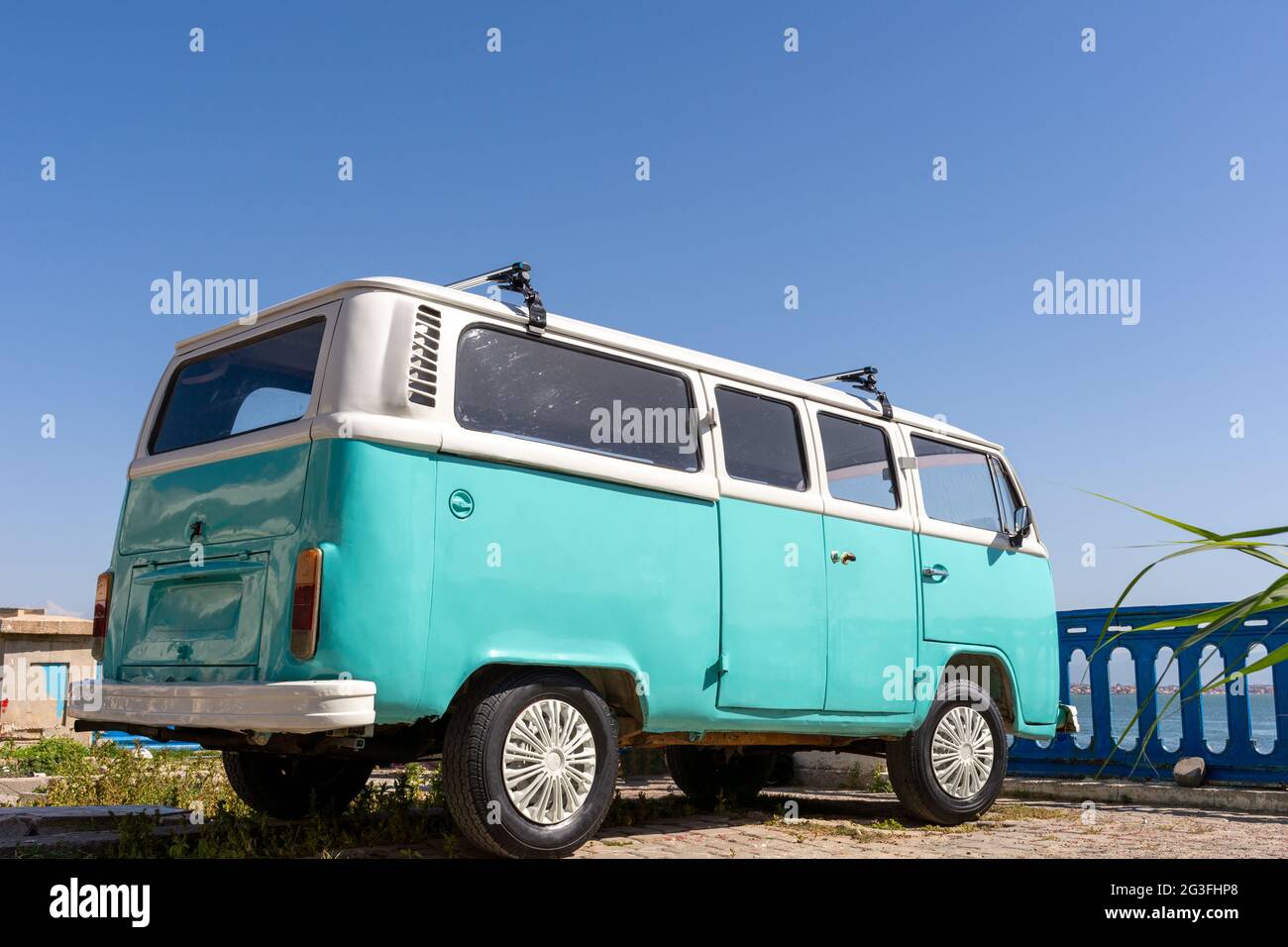 Vista ad angolo basso del turchese Volkswagen van parcheggiato vicino alla spiaggia, concetto di vacanza estiva. Foto Stock