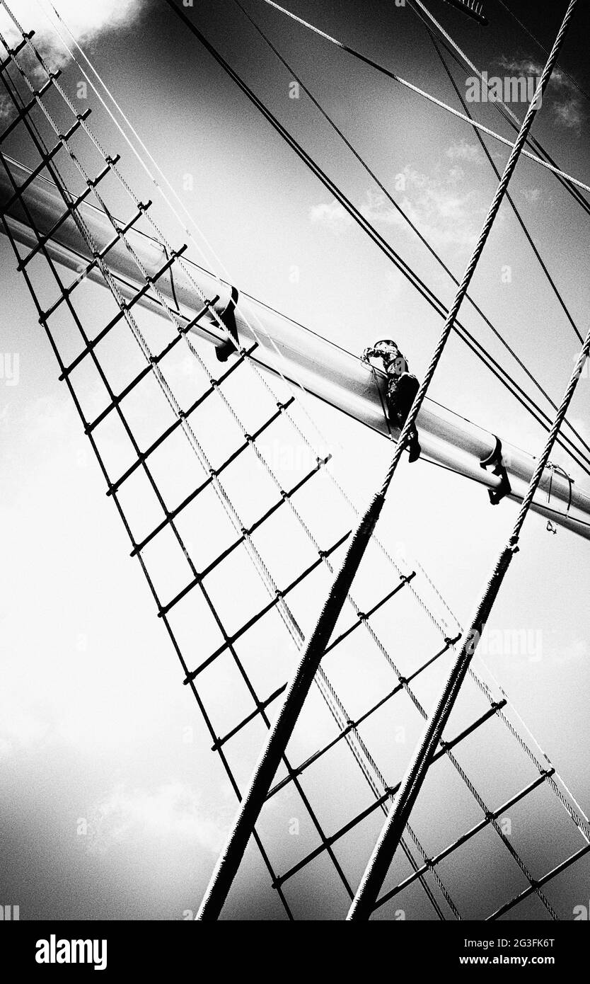 uomo aloft su tradizionale barca a vela quadrata Foto Stock