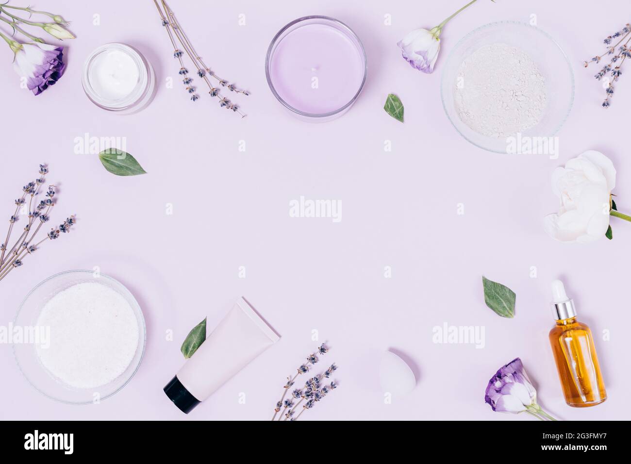 Set relax con cosmetici biologici, candela aromatica, sale da bagno, fiori secchi di lavanda, bottiglia d'olio essenziale, argilla asciutta e idratante su lil leggero Foto Stock