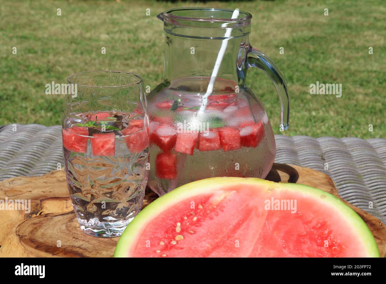 d'estate vibes con vetro e decanter di acqua melone infondere ghiaccio e mezzo melone d'acqua sul lato Foto Stock