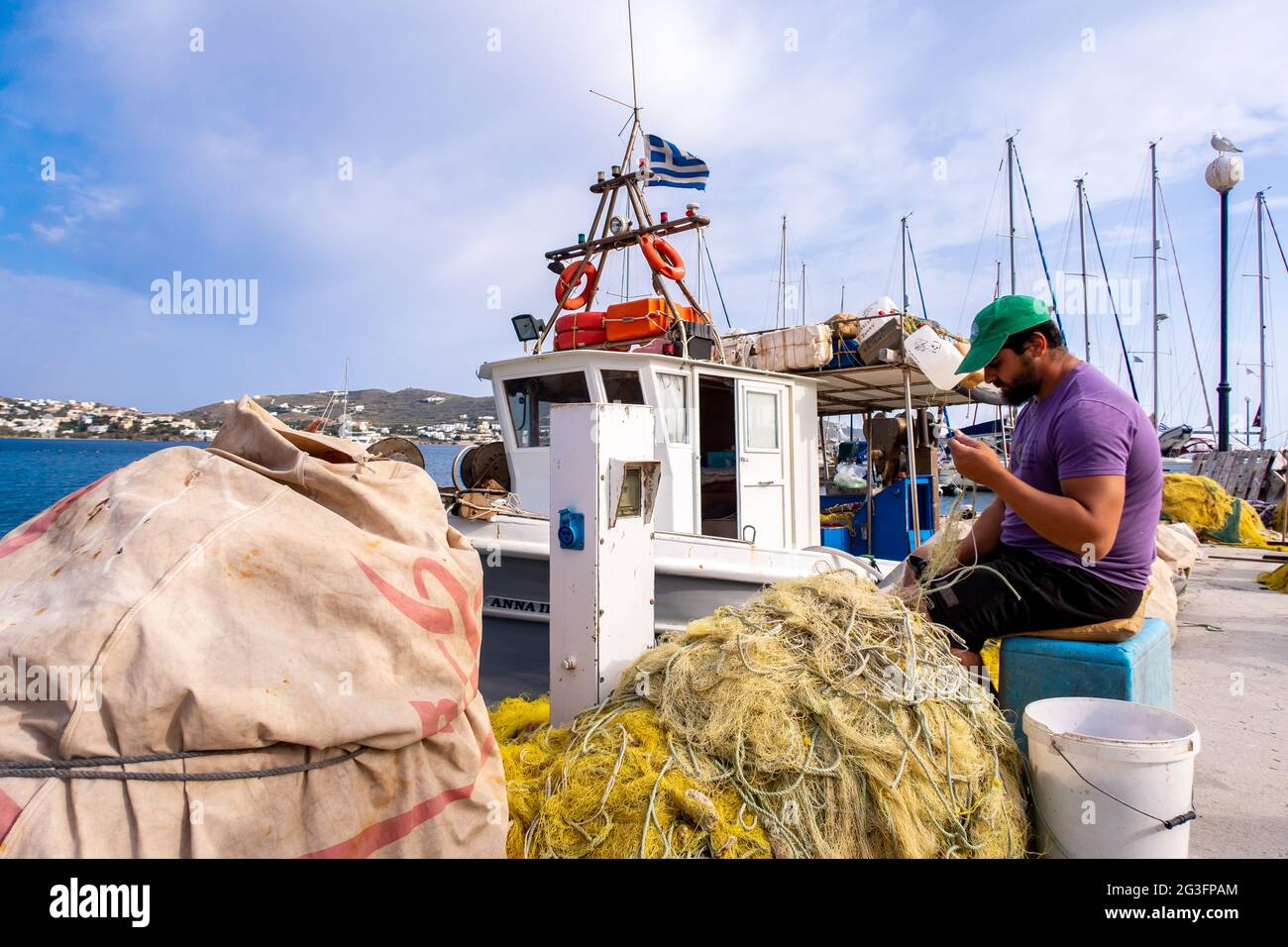 FINIKAS, SIROS, Grecia, 27.05.2019. Il pescatore greco che ripara le sue reti da pesca di nylon sul molo nel porto di Finikas sull'isola di Siros, Cicladi, Grecia. Foto Stock