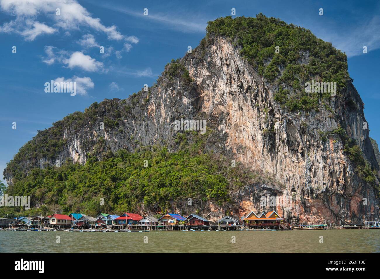 Spettacolari formazioni rocciose e scogliere con un villaggio d'acqua costruito su palafitte, a Phang Nga Bay Thailandia Foto Stock