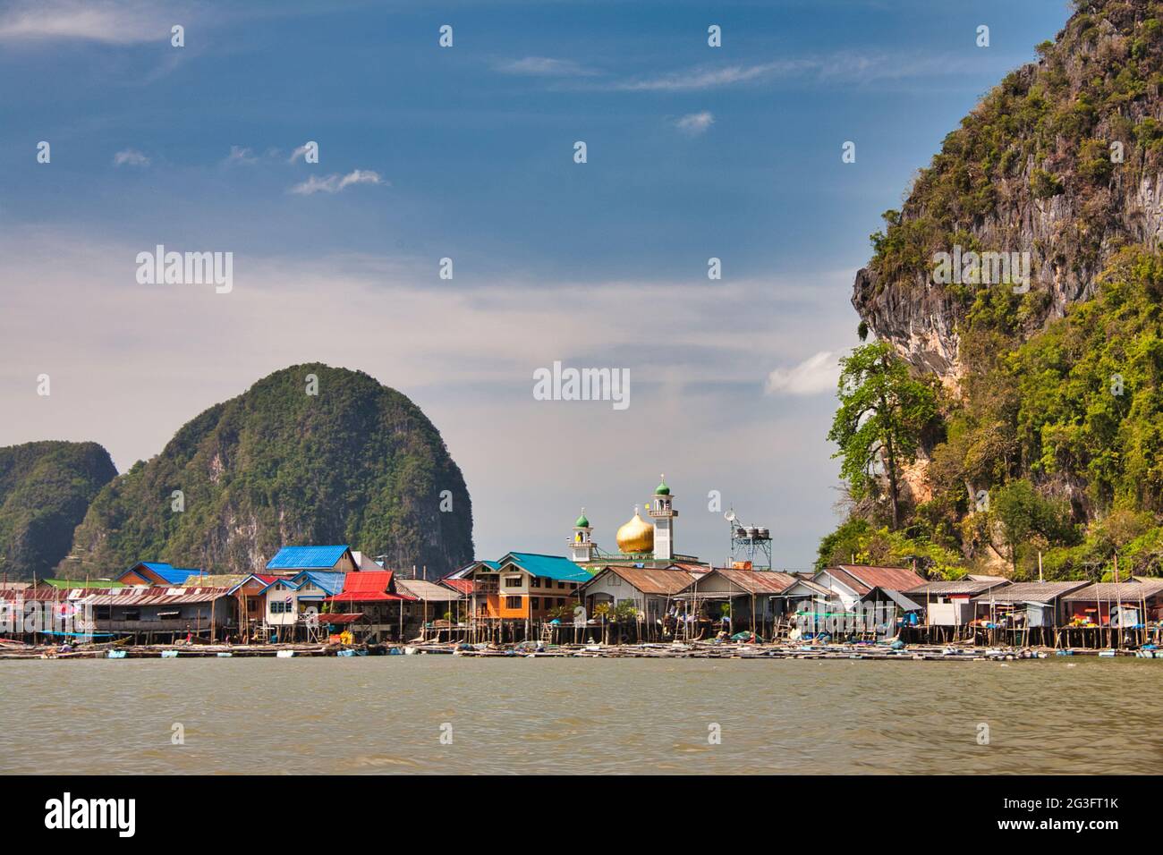 Spettacolari formazioni rocciose e scogliere con un villaggio d'acqua costruito su palafitte, a Phang Nga Bay Thailandia Foto Stock