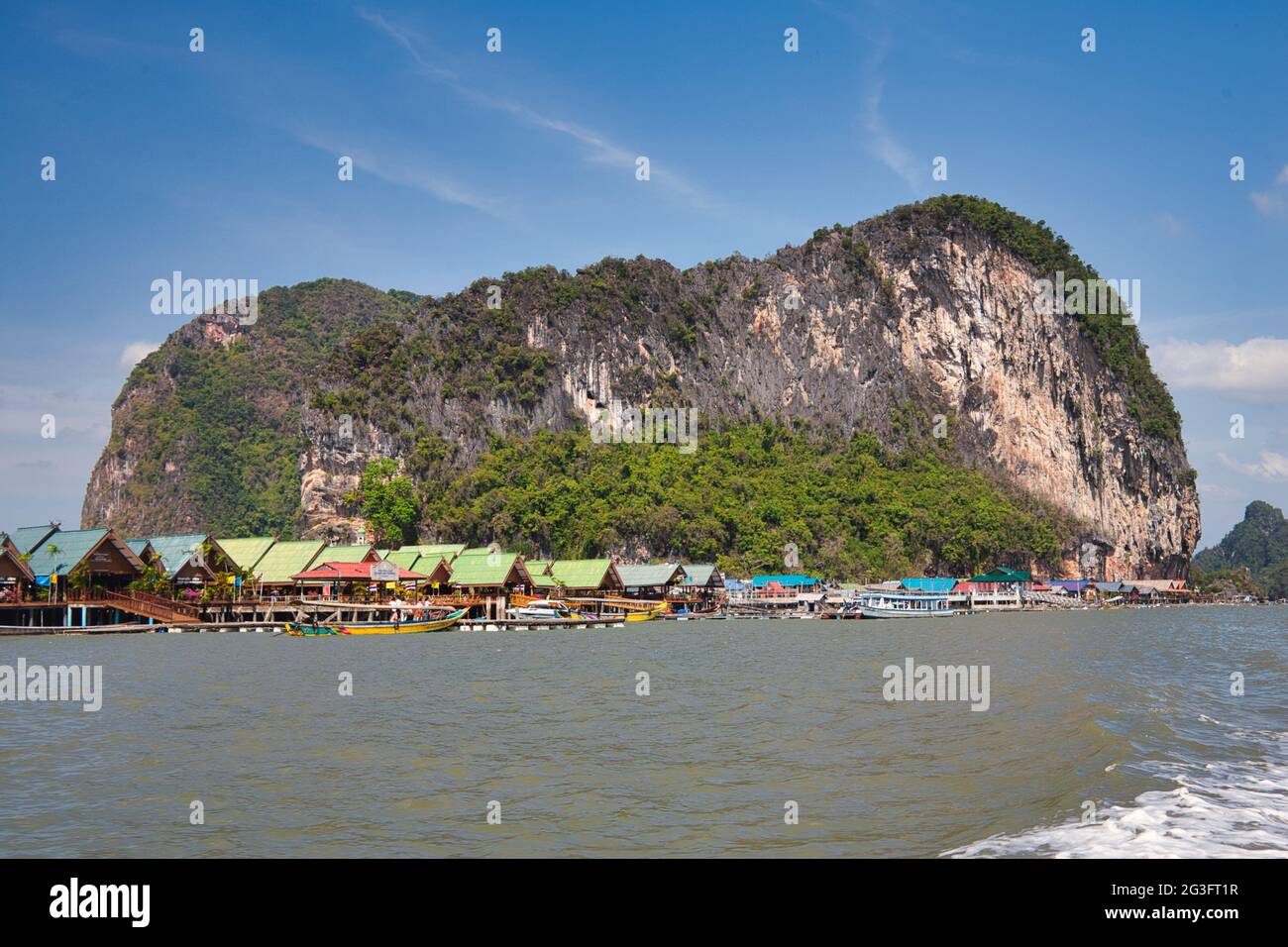 Spettacolari formazioni rocciose e scogliere con un villaggio d'acqua costruito su palafitte, a Phang Nga Bay Thailandia Foto Stock