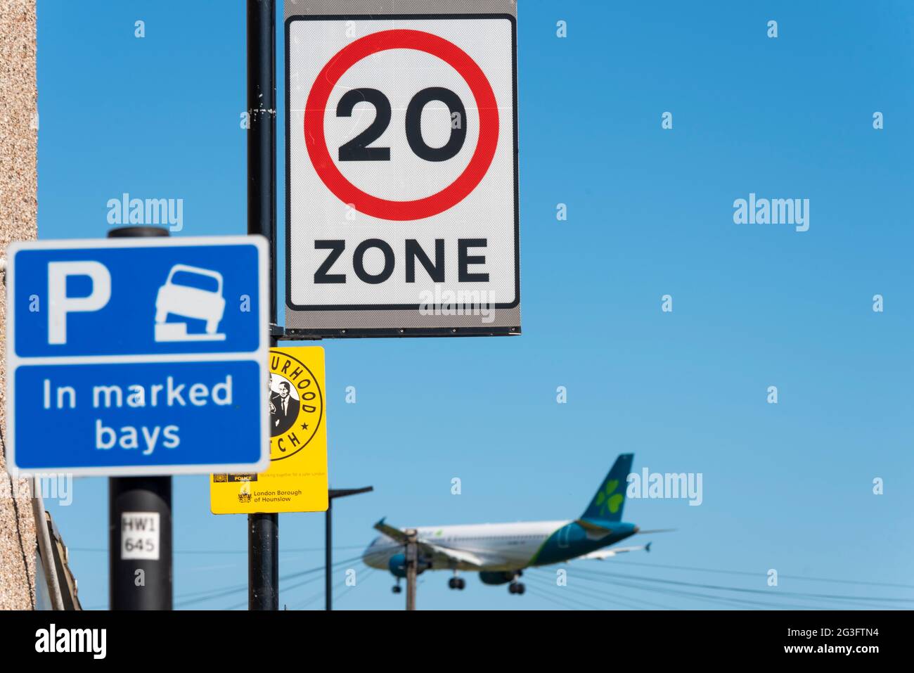 Aereo di linea aerea Aer Lingus in finale per atterrare all'aeroporto Heathrow di Londra, Regno Unito. Passaggio su un'area residenziale con limite di velocità, aree di parcheggio. 20 mph Foto Stock
