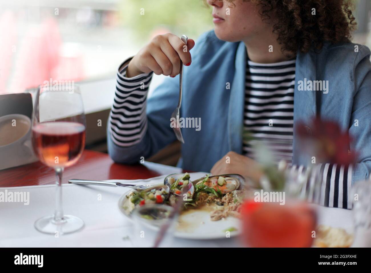Crop anonima donna seduta a tavola con un bicchiere di vino e mangiare deliziose ostriche nel ristorante Foto Stock