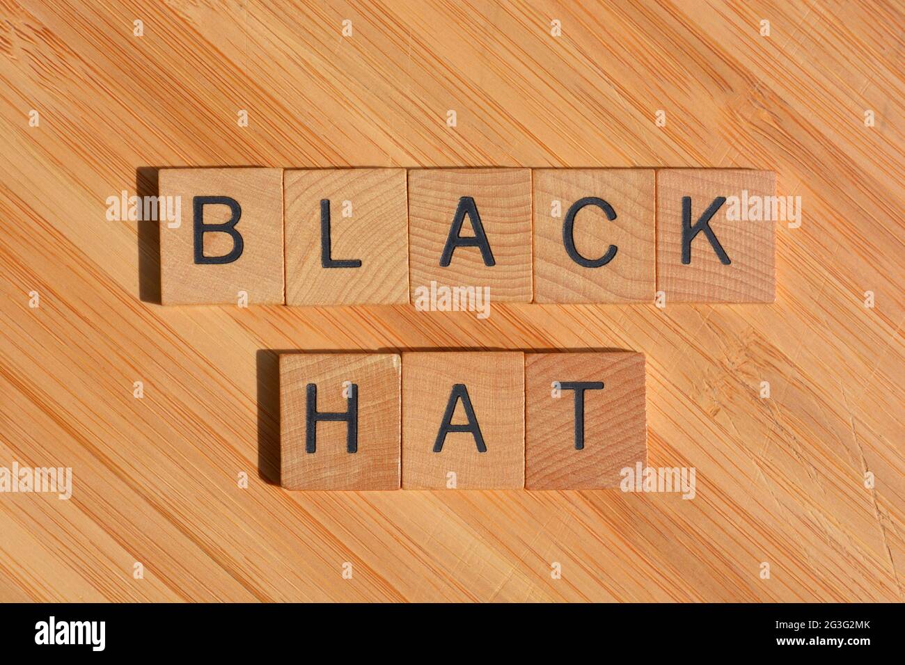 Cappello nero, parola d'ordine in lettere alfabetiche in legno isolate su sfondo di legno di bambù Foto Stock